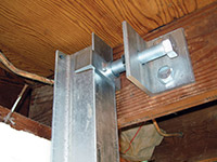 Securing the i-beam system to the top of the floor joist in a foundation wall repair in Mason.
